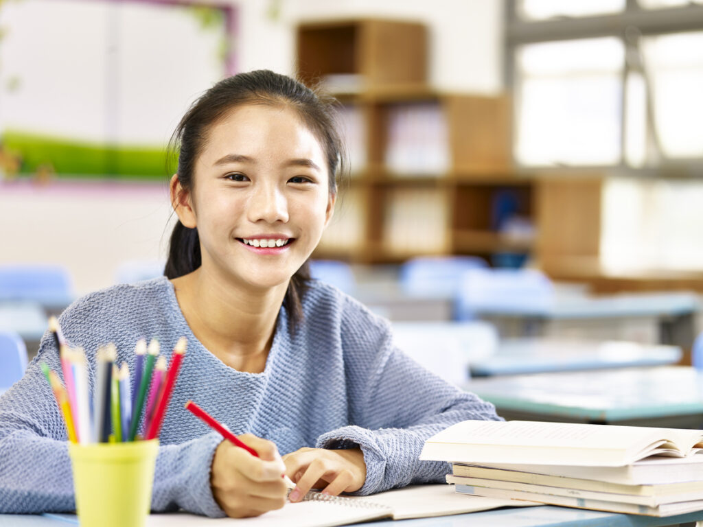 こちらを見て笑うアジア人の女子学生